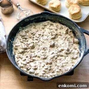 Creamy Sausage Gravy for Biscuits: Homemade Southern Recipe 9 a cast iron skillet of gravy sausage with a pan of biscuits in the background.