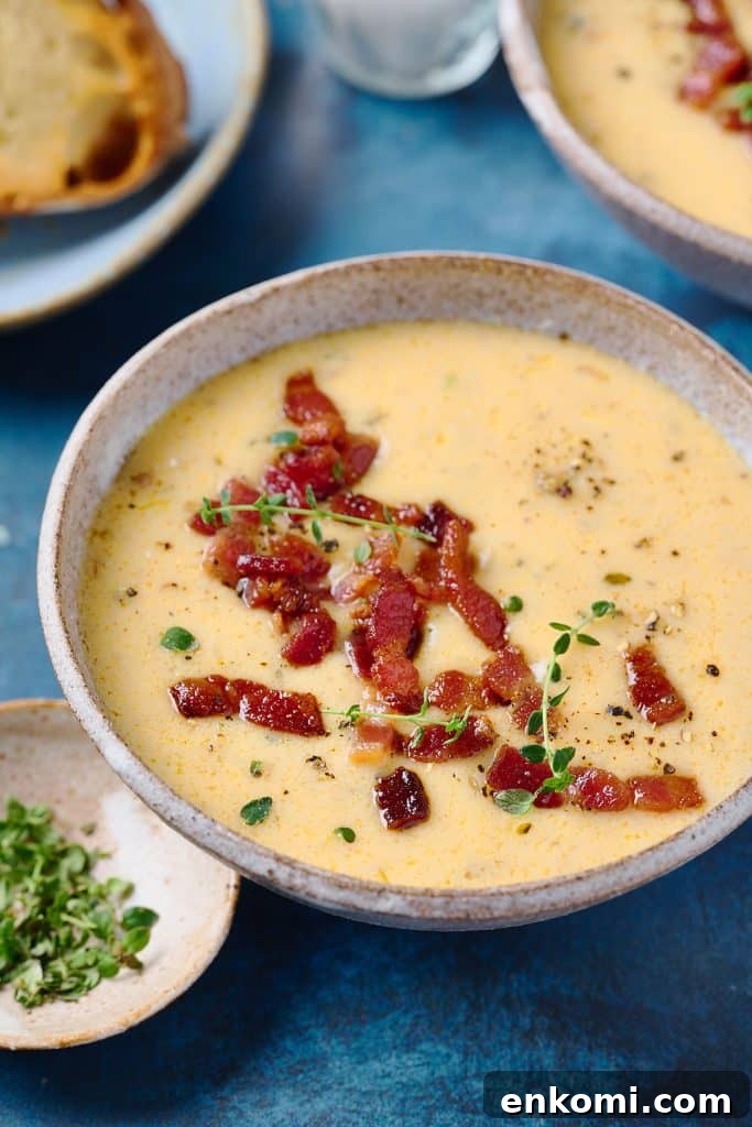 Bowl of creamy soup topped with crispy bacon and garnished with fresh thyme leaves
