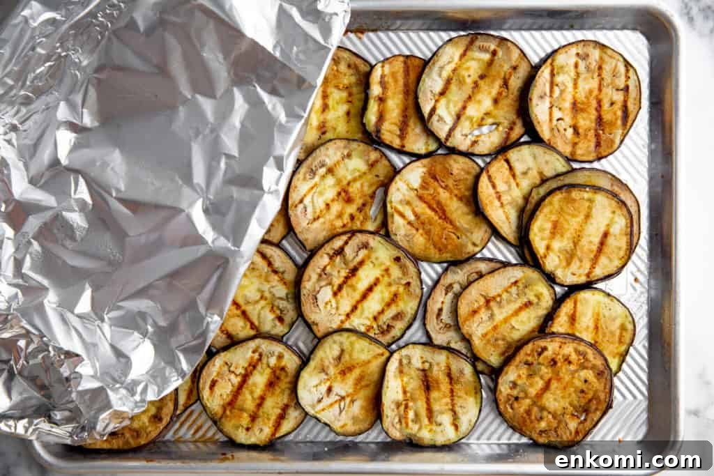 Greek-Style Grilled Eggplant Salad with Simple Grilling Tips 7 Process shot showing eggplant slices covered with foil on a sheet pan.