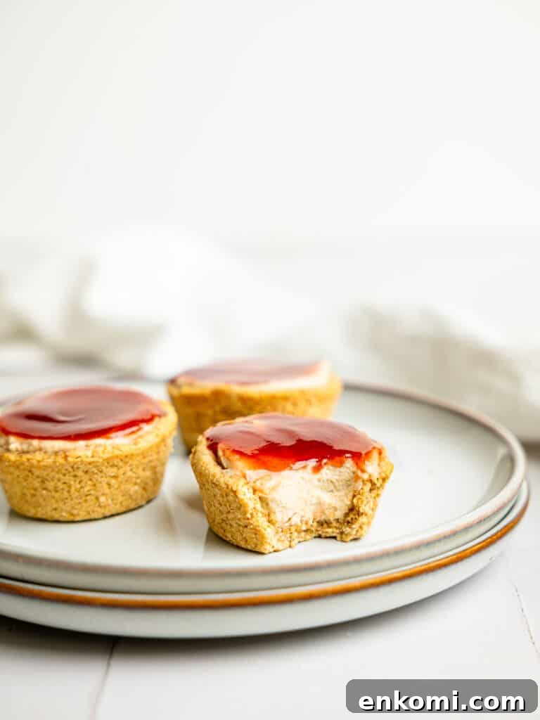 High-Protein Mini Cheesecakes: Low-Calorie Dessert Recipes 5 Three mini protein cheesecakes on a plate, one is half-eaten.