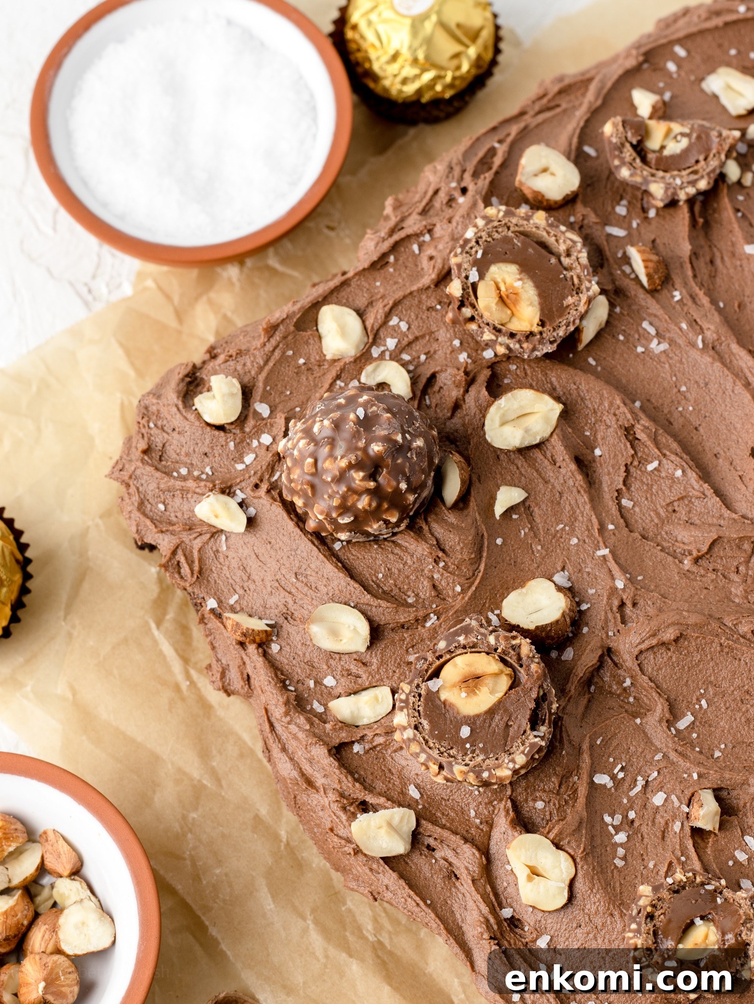 Closeup of toppings, Ferrero Rochers, hazelnuts, flaky sea salt.