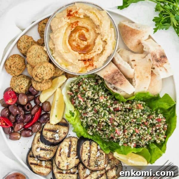 Hummus, falafel, tabbouleh, and grilled eggplant on a plate.