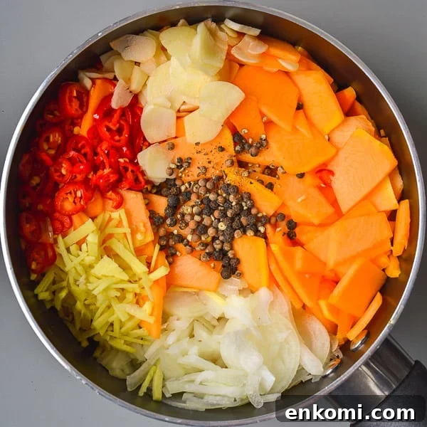 Saucepan with sliced pumpkin, onions, ginger, red chili peppers, garlic and black peppercorns