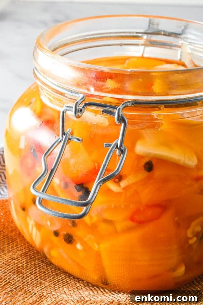 Side view of preserves jar filled with orange vegetables and garlic
