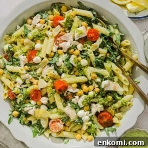 Chicken pesto pasta salad tossed on a scalloped white bowl.