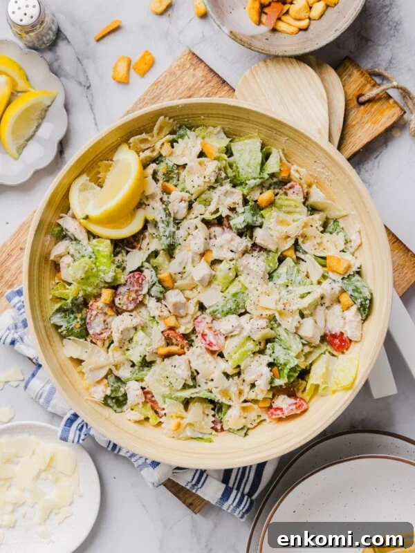 Chicken caesar pasta salad tossed in a large bamboo mixing bowl.