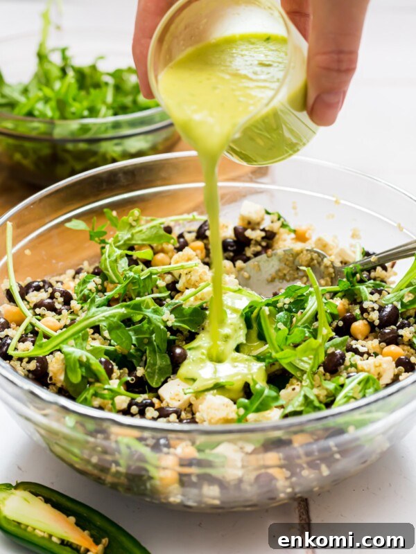 Quinoa and arugula salad with honey jalapeno green dressing being poured over