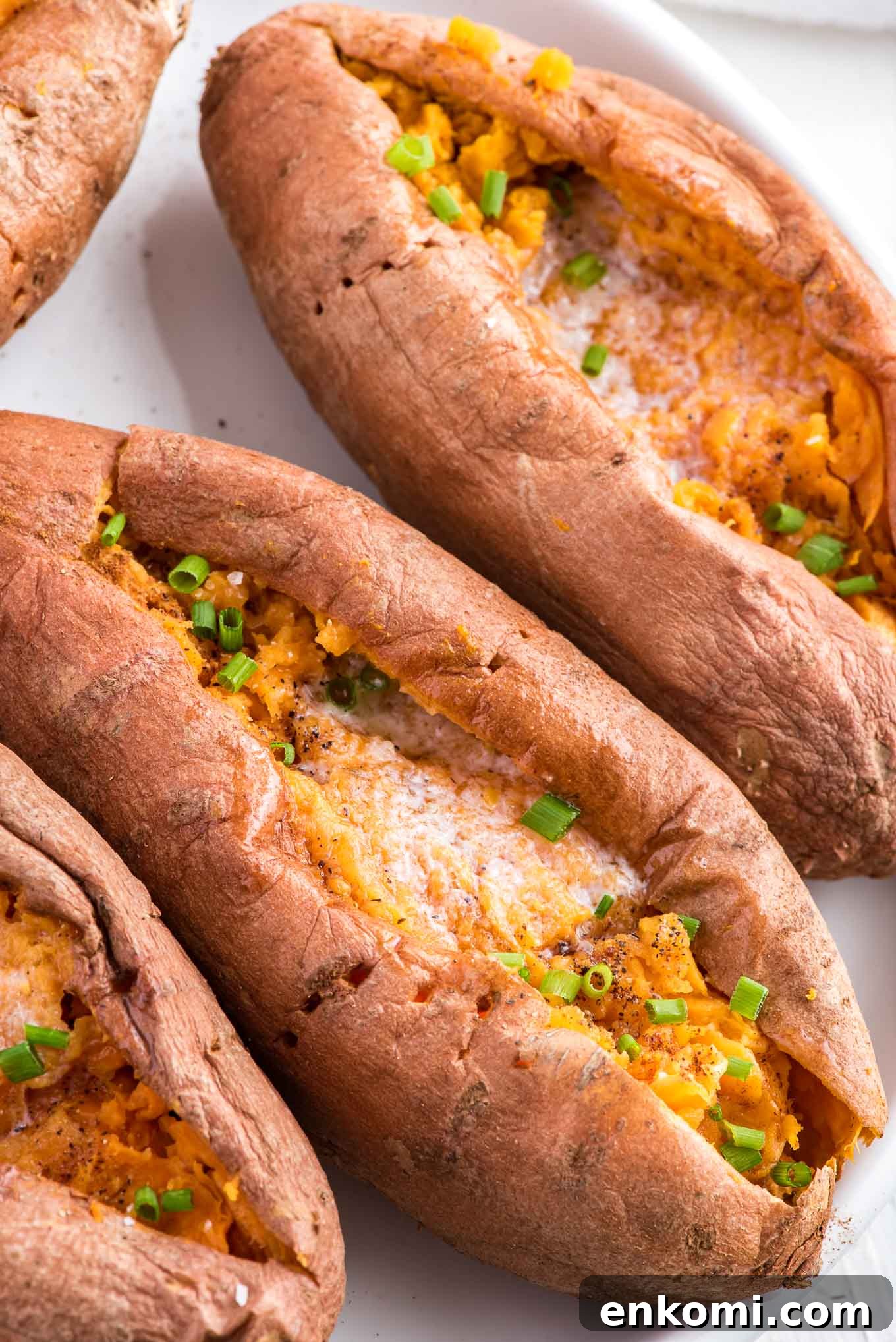 An overhead image of the sweet potatoes cut open with melted butter and green onions on top.