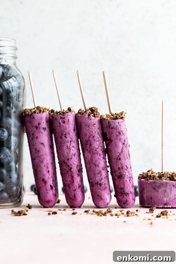 Side view of blueberry goat cheese ice cream bars propped up next to a jar of blueberries.