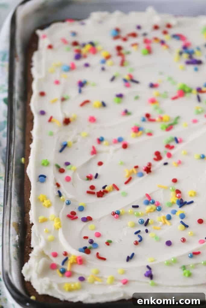 Chocolate cookie bars in a baking dish topped with vanilla frosting and sprinkles.