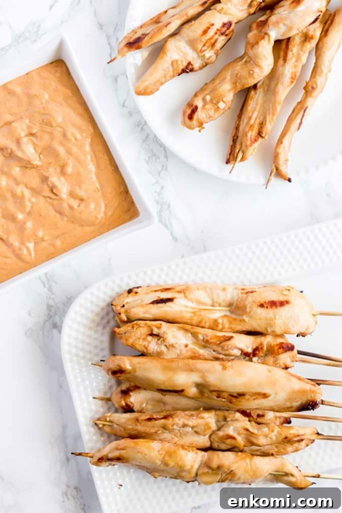 Plates of Chicken Satay next to a bowl of peanut dipping sauce