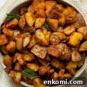 Extra cispy oven roasted potatoes with golden brown edges, garnished with fresh rosemary sprigs and flaky sea salt.