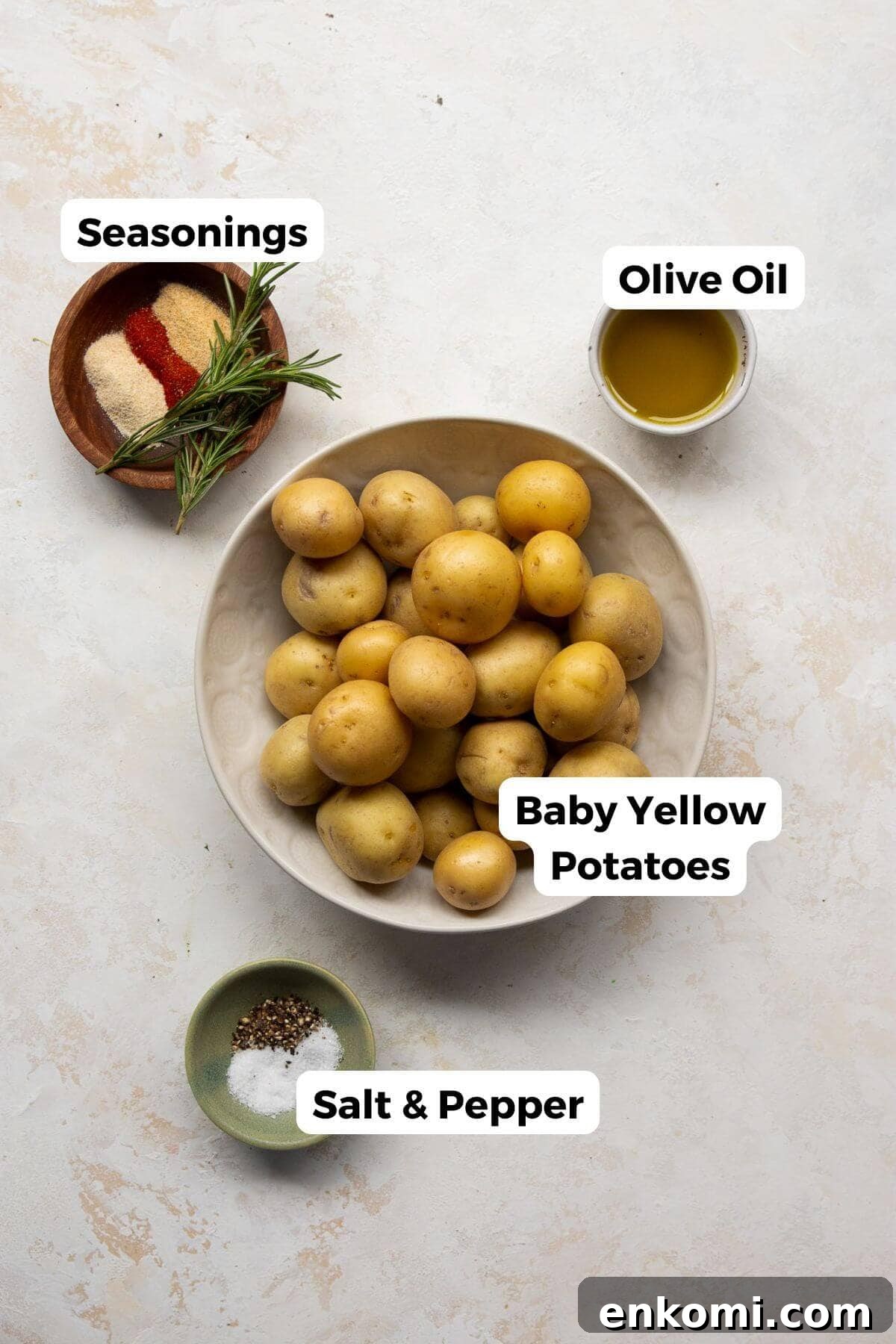 Ingredients for crispy oven roasted potatoes including baby Yukon gold potatoes, olive oil, paprika, garlic powder, and fresh rosemary.