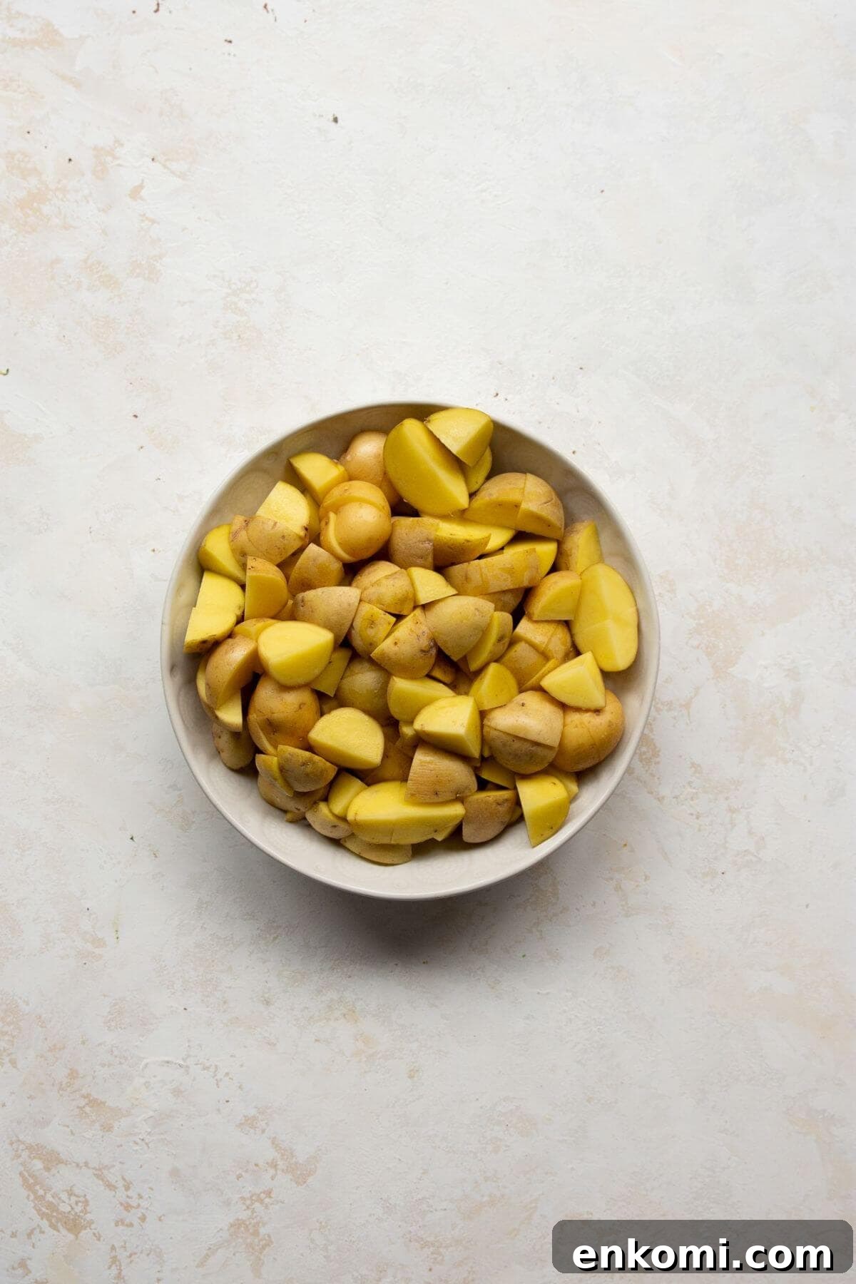 Baby Yukon gold potatoes cut into 1-inch cubes in a metal bowl, ready to parboil.
