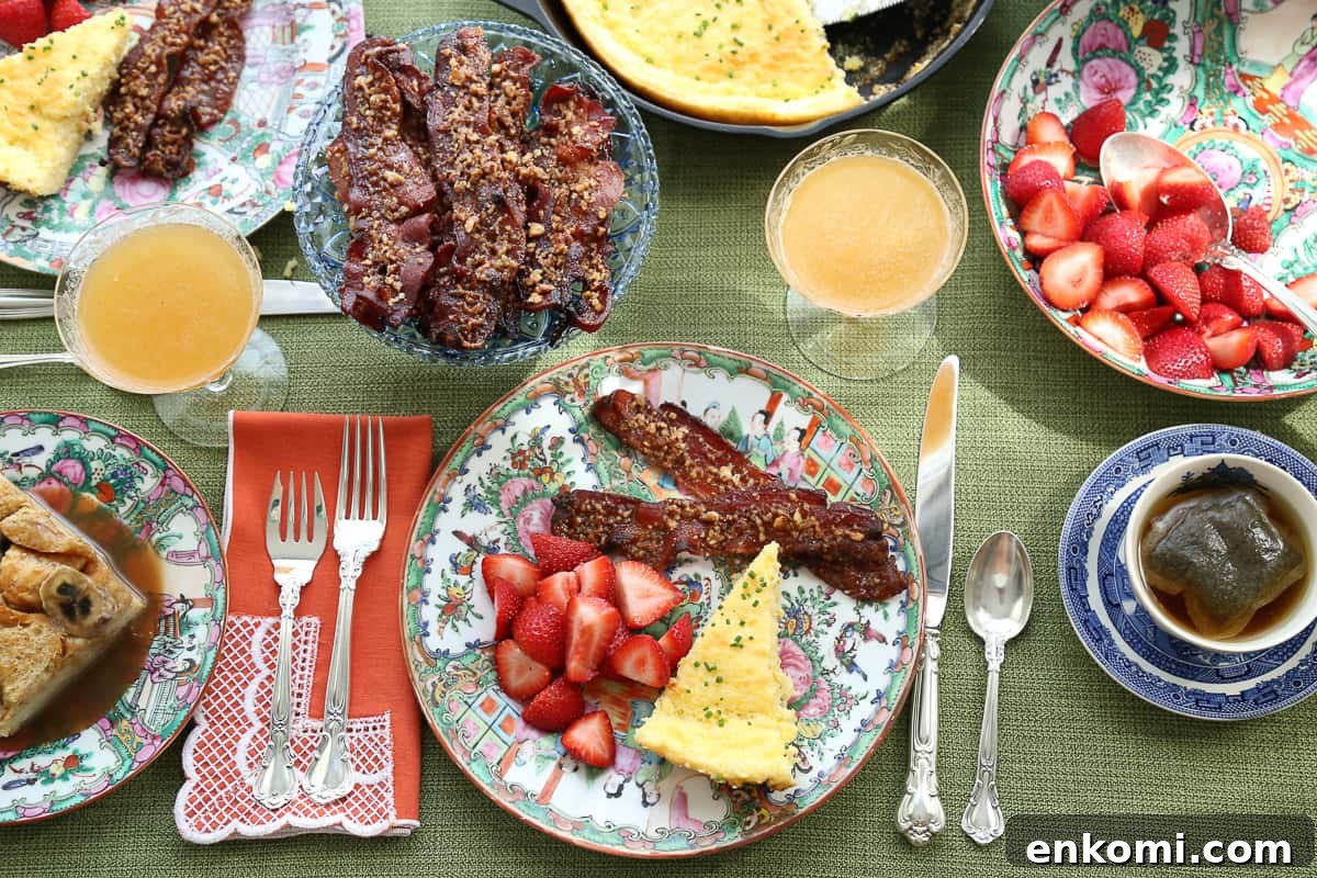 table set for brunch with colorful china, silverware, bacon, spoon bread, and strawberries.