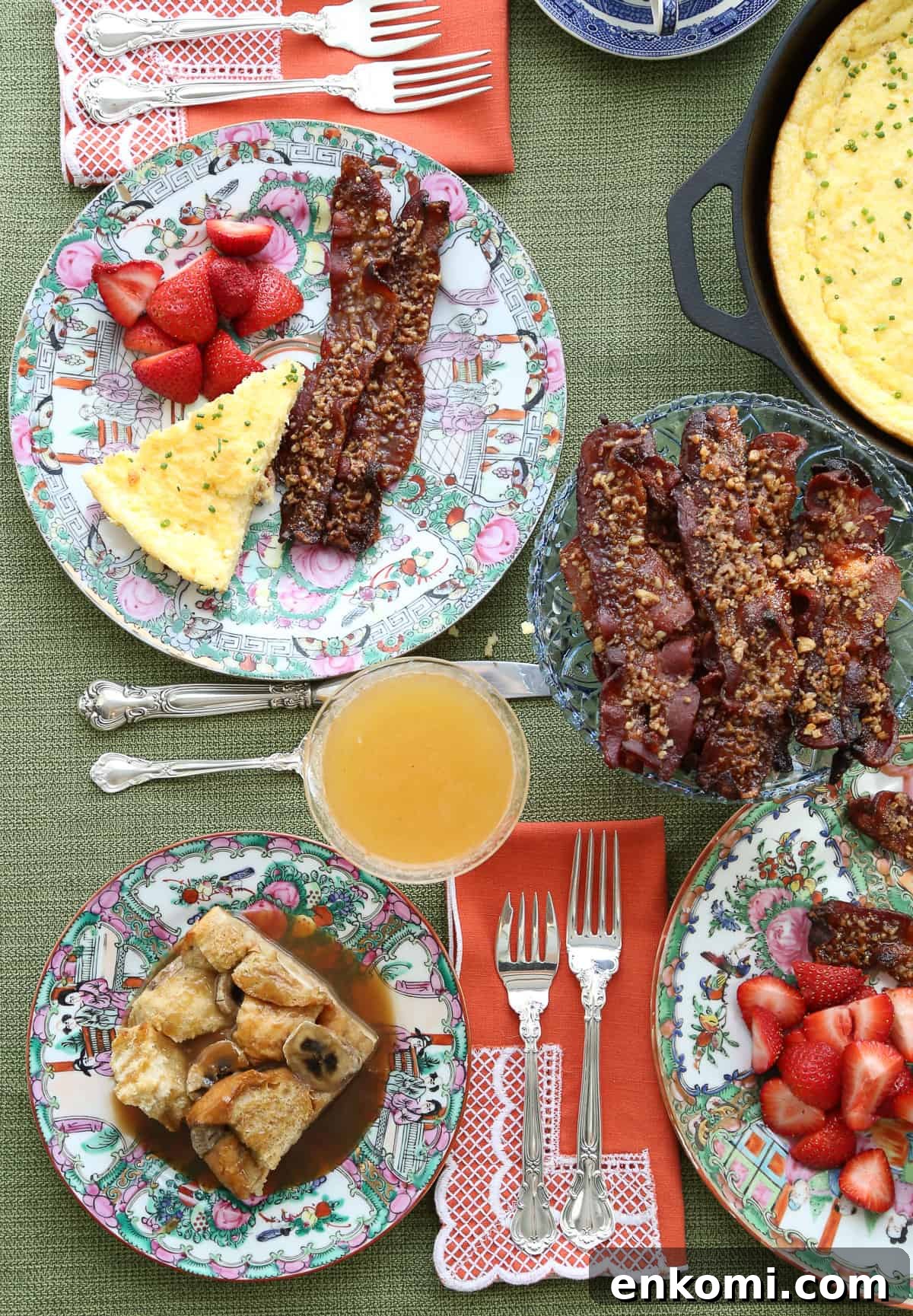 table set for brunch with berries, bacon, bellinis, and french toast casserole on china plates.