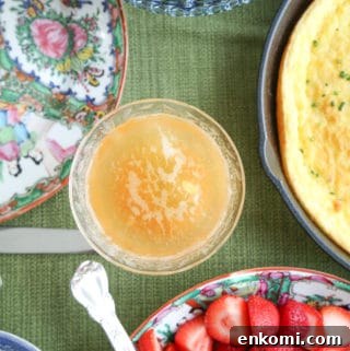 bellini in a coupe glass on a green tablecloth surrounded by brunch foods