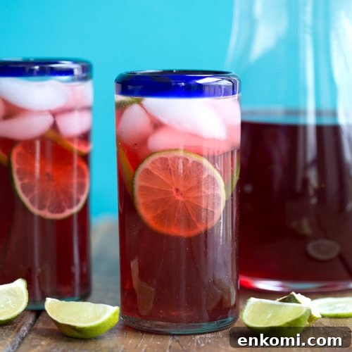 glass of hibiscus iced tea with limes