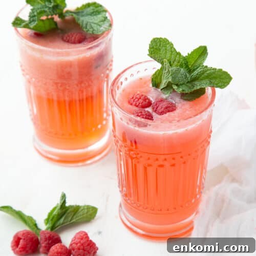 two glasses of raspberry lemonade garnished with fresh mint.