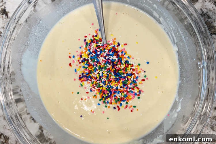 Homemade Funfetti Waffles Recipe for Soft, Colorful Breakfast 3 waffle batter in a mixing bowl with rainbow colored sprinkles