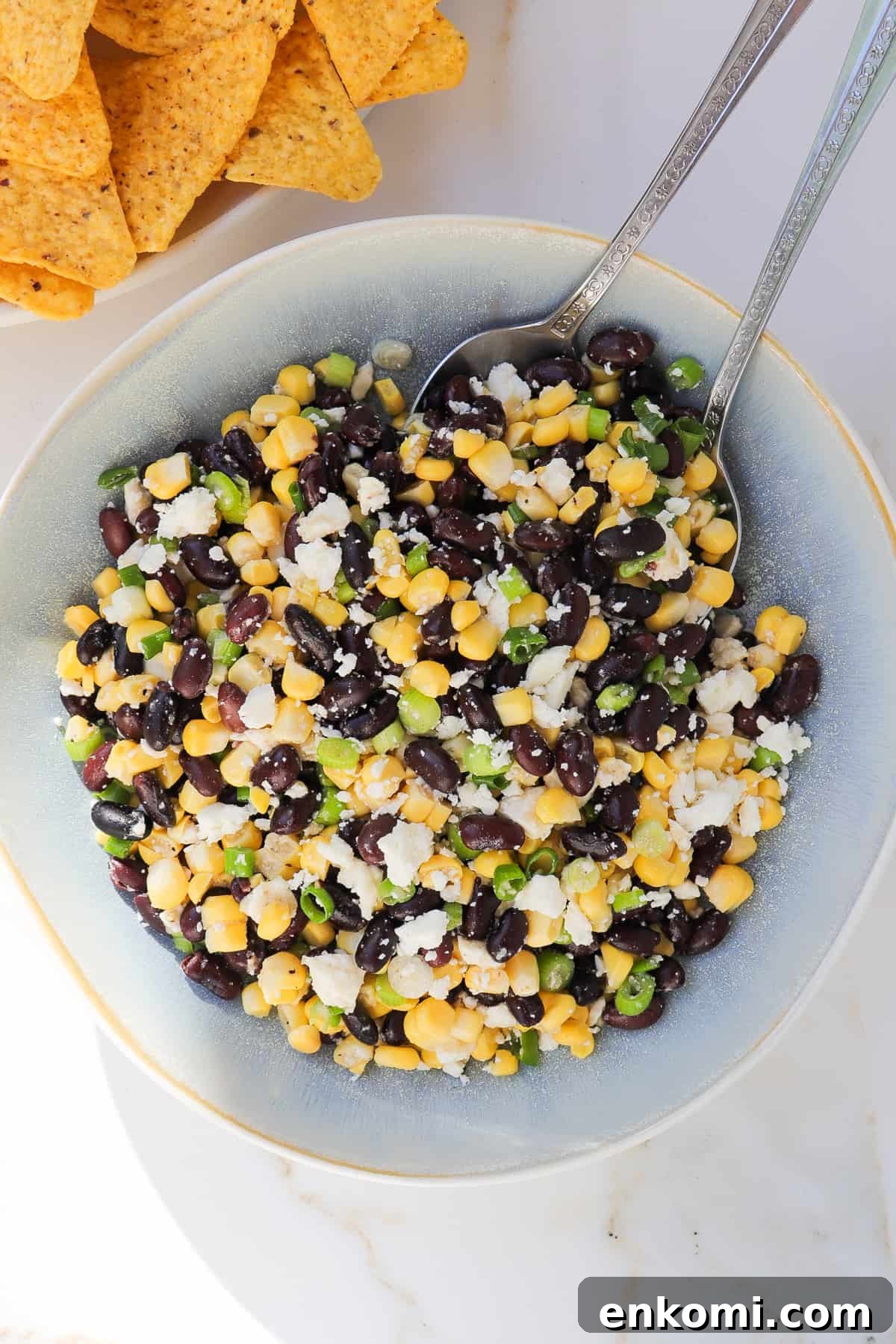 Fresh corn, black bean feta dip with spoons. Tortilla chips on the side.