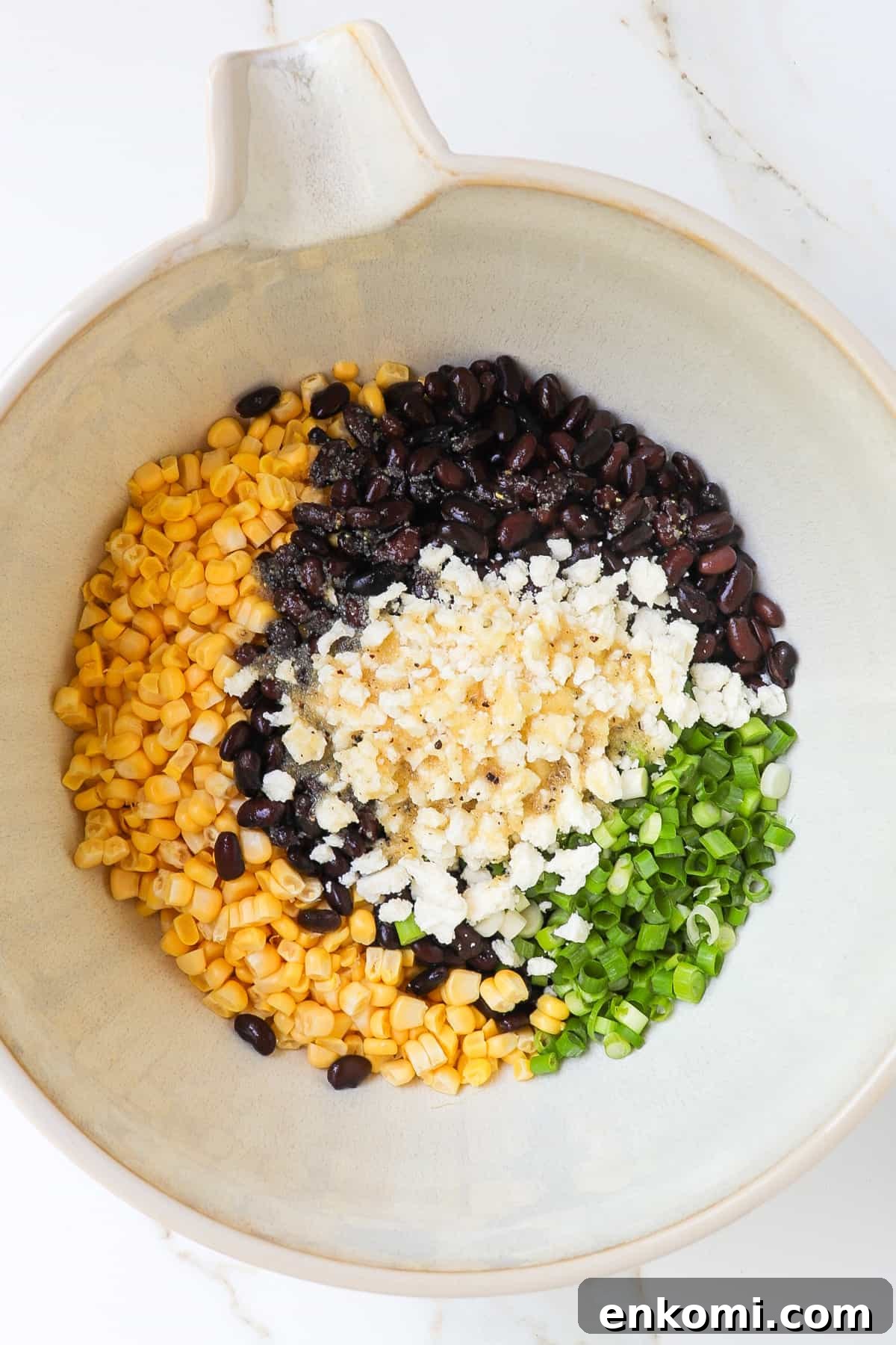 Fresh corn, black beans, crumbled feta cheese, spring onions and dressing in a large mixing bowl.