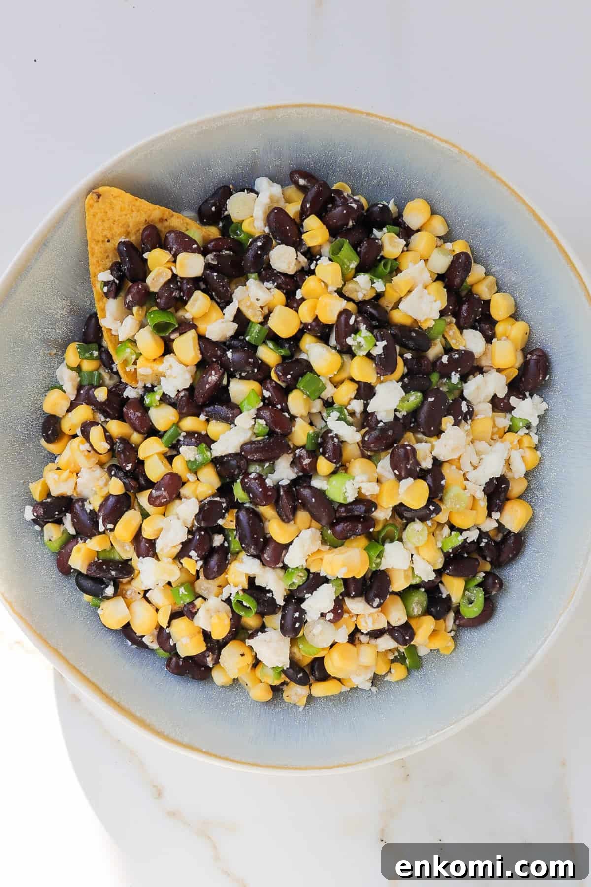 Black bean corn feta dip with a tortilla chip in the bowl.