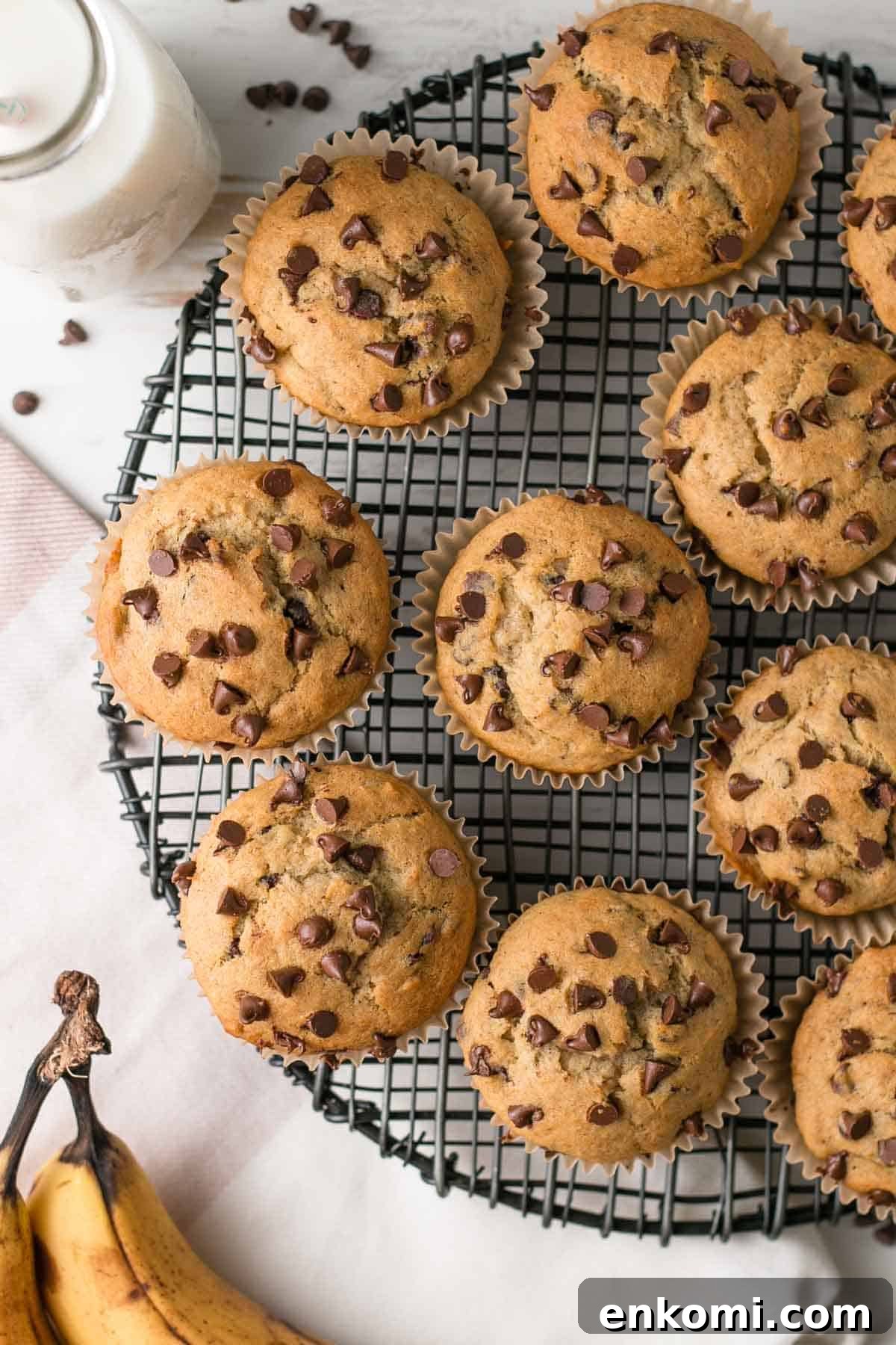 Muffins studded with chocolate chips on a black wire rack.