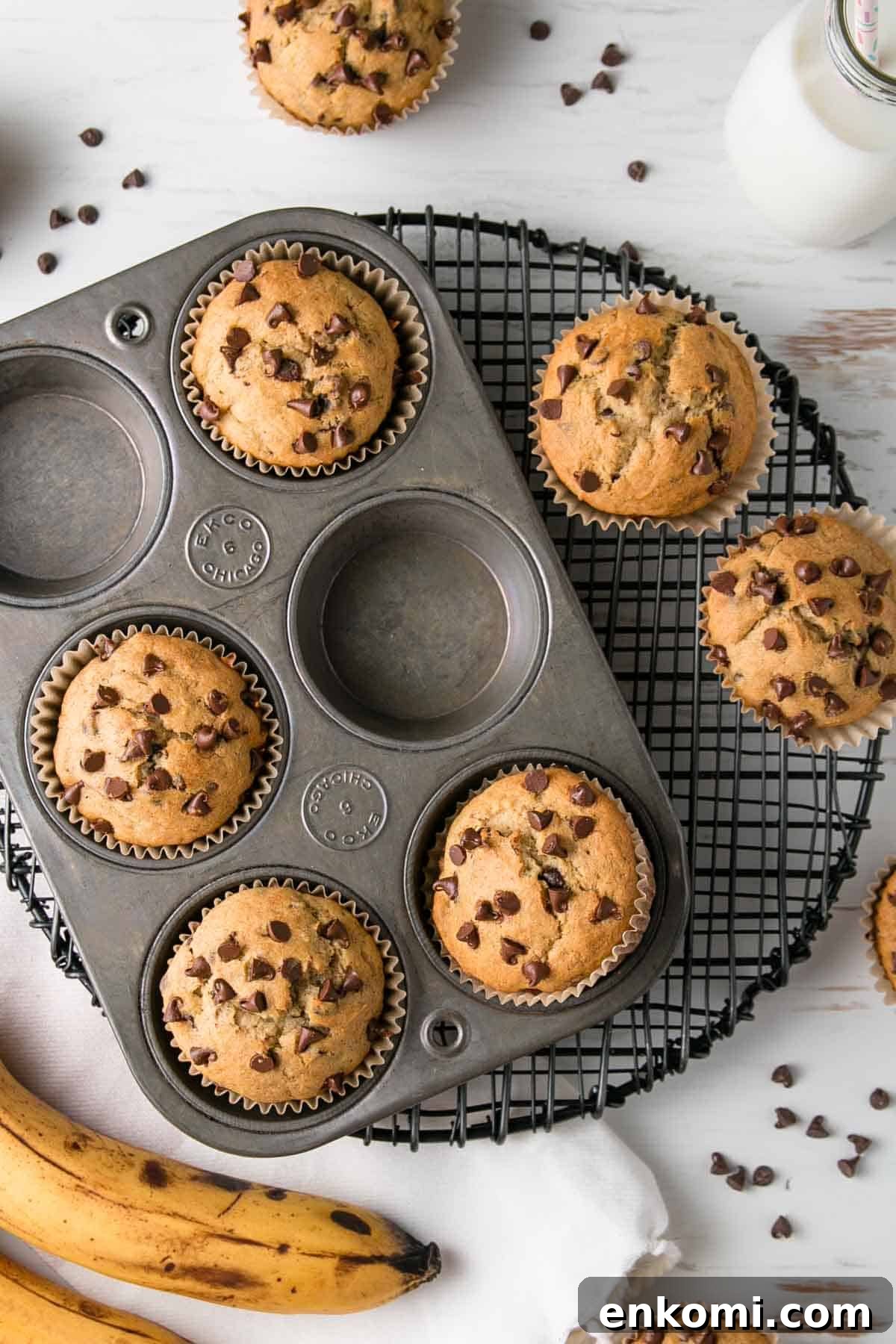 Muffins in an old muffin tin next to bananas and chocolate chips.