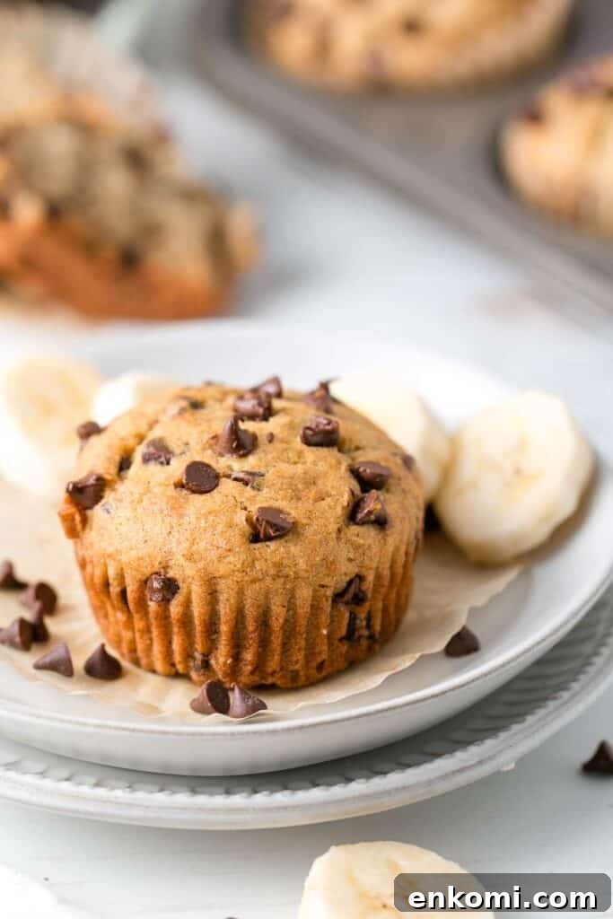 A muffin on a plate with banana slices and chocolate chips.