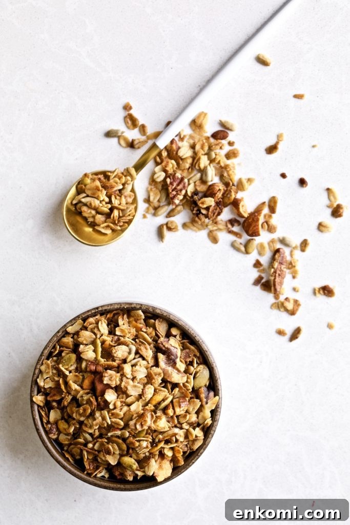 Homemade granola in a bowl, on a spoon, and on a countertop.