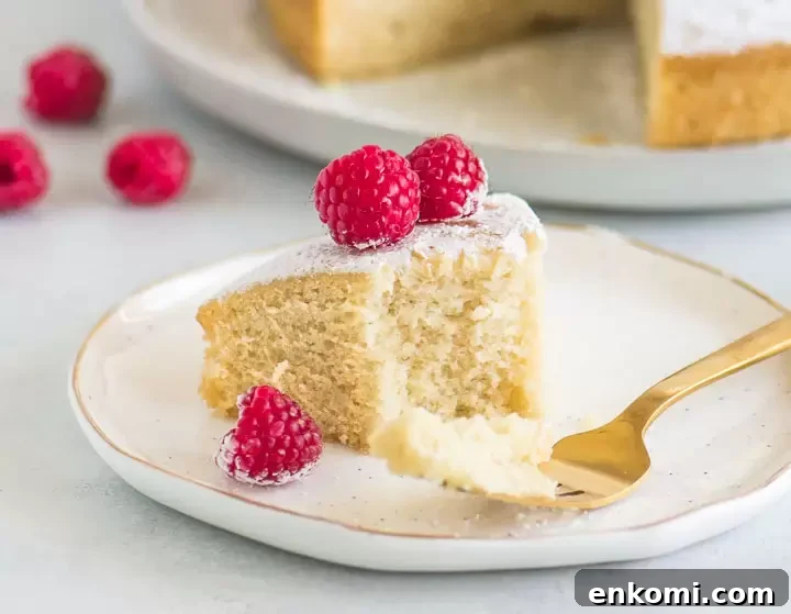 slice of cake on a plate with a fork taking a bite out of it and the rest of the cake in the background