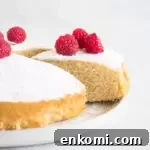 sliced cake on a cake plate with powdered sugar and raspberries on top