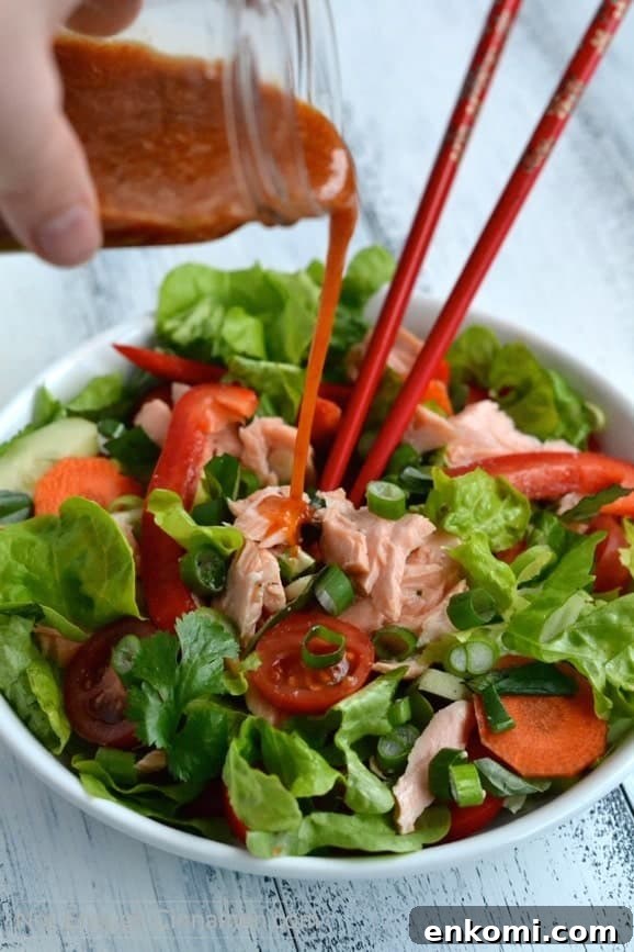 Thai Salmon Salad with Tangy Sweet Chili Dressing 4 Sweet Chili Sauce Dressing being poured on top of a Thai Salmon Salad in a white bowl