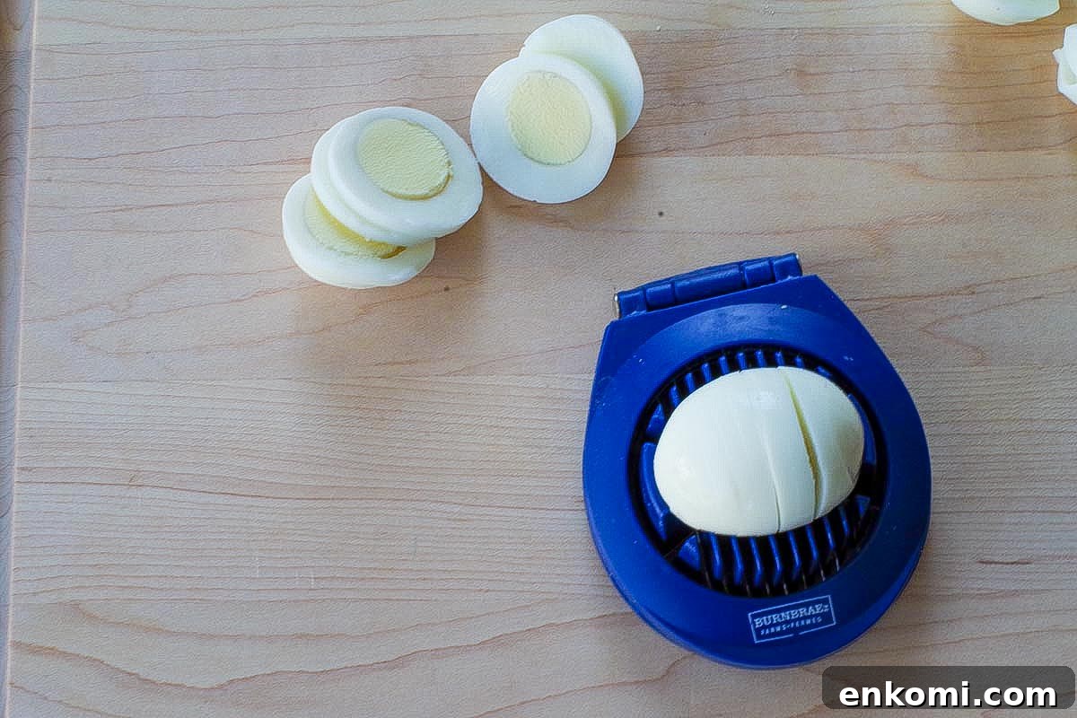 Weight Watchers Potato Salad Recipe — Light & Flavorful 11 Egg being sliced with an egg slicer and more sliced eggs behind it on the cutting board.