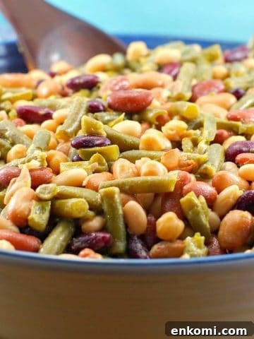 Easy (vegan) mixed bean salad in a large bowl with a dark brown wooden spoon