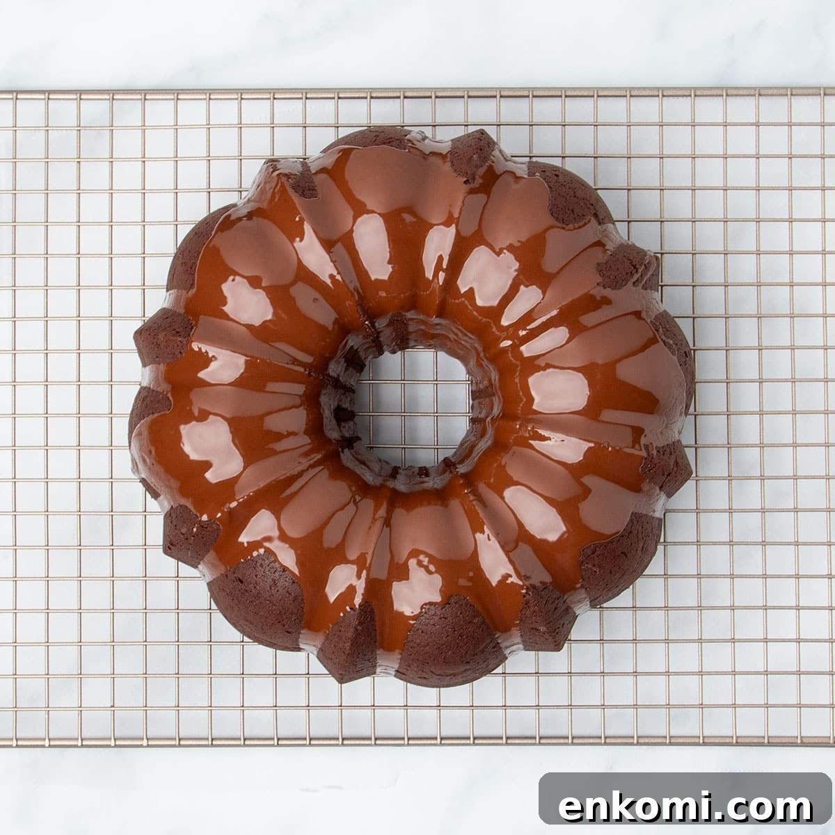 shiny wet light brown chocolate glaze poured on top of baked overturned bundt cake on wire rack