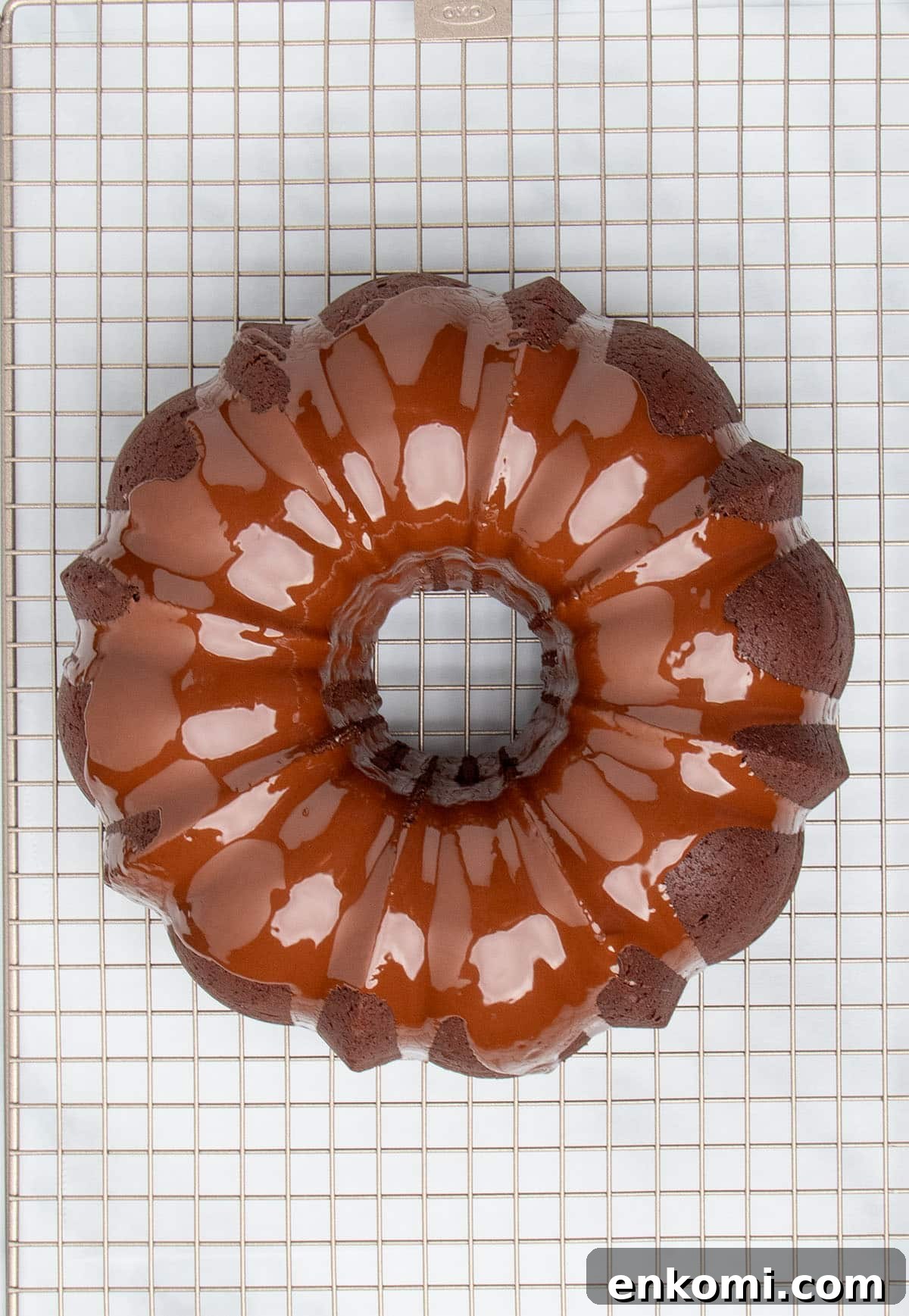 overhead image of fresh shiny brown chocolate glaze on dark brown chocolate bundt cake on gold colored wire rack