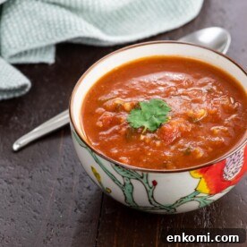 spiced tomato soup with red lentils in a bowl with a spoon and napkin