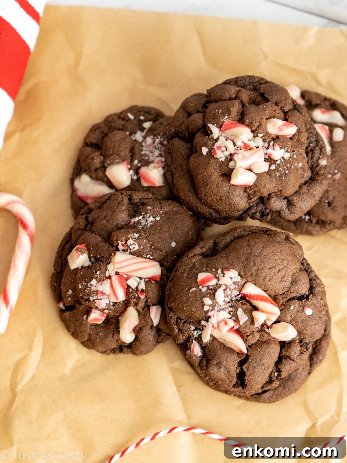 Chocolate cookies topped with crushed candy canes on brown parchment paper.