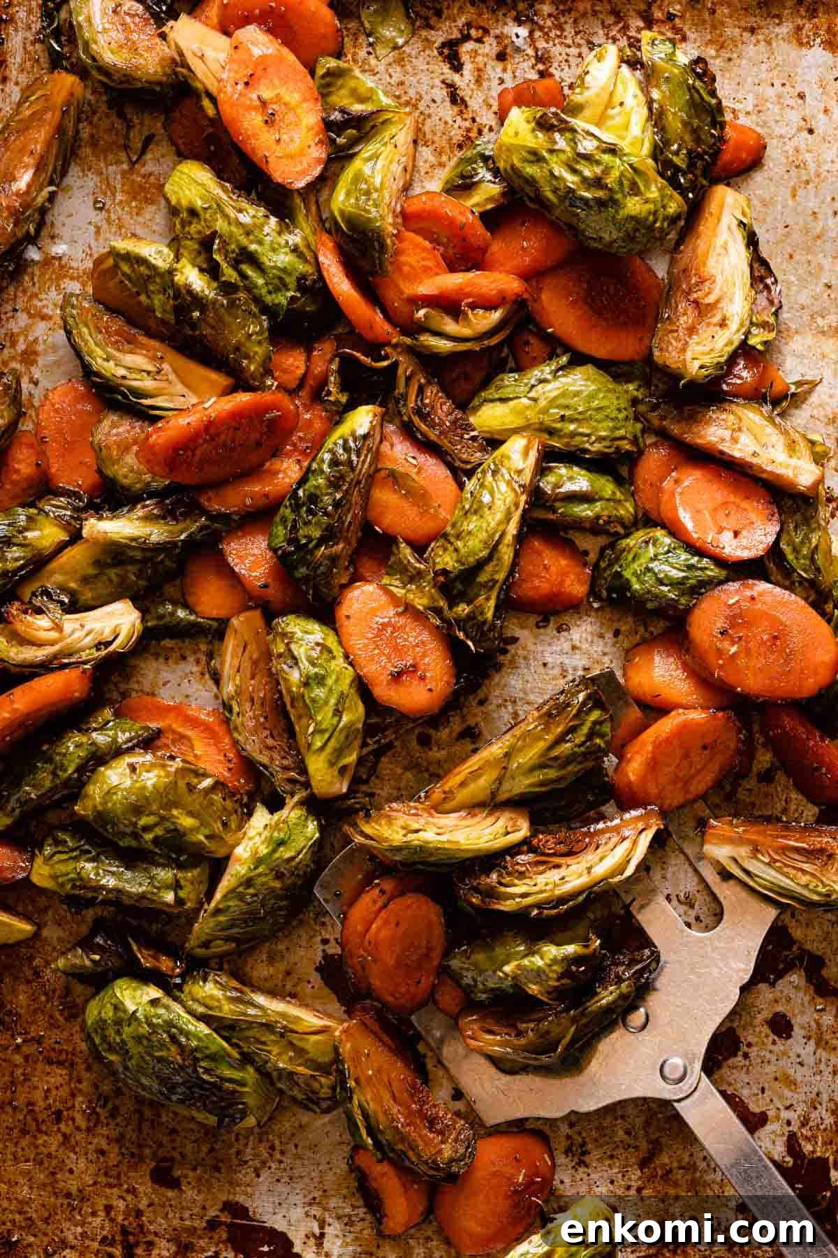 roasted brussels sprouts and carrots on metal pan with spatula on the side