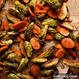 roasted brussels sprouts and sliced carrots on baking pan with spatula on the side