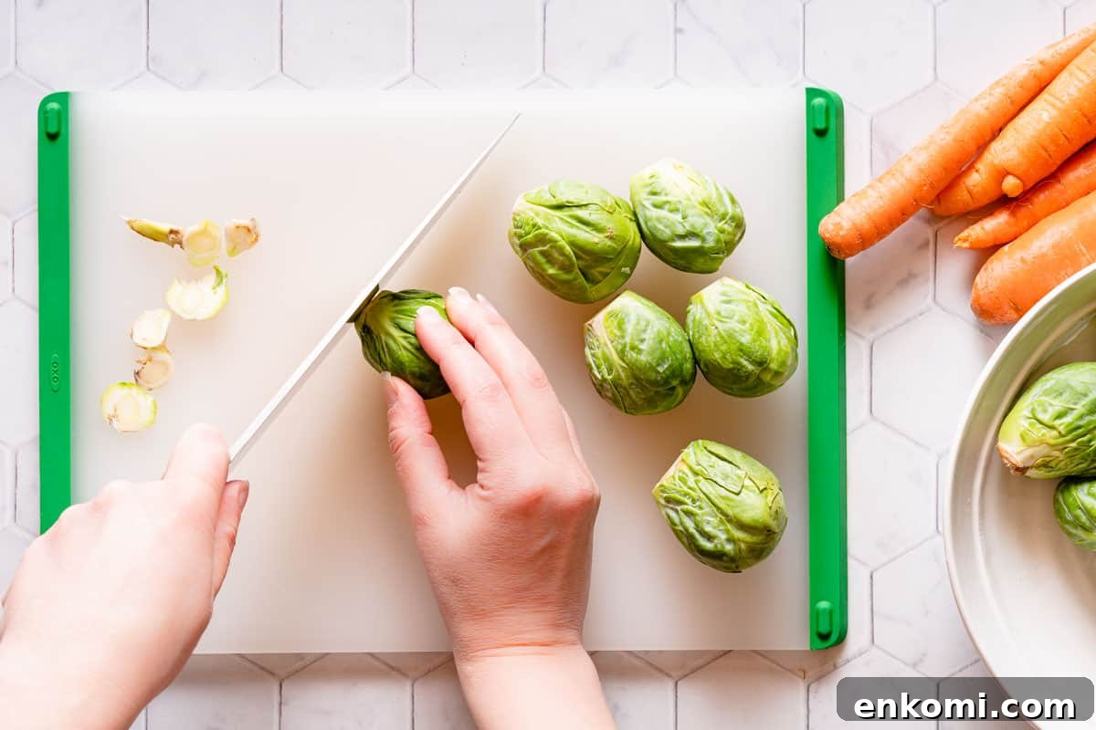 end of brussels sprout being cut off with knife with carrots on the side