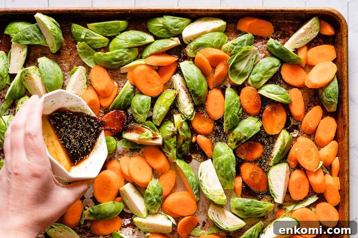 small bowl of balsamic glaze being poured onto veggies on baking pan