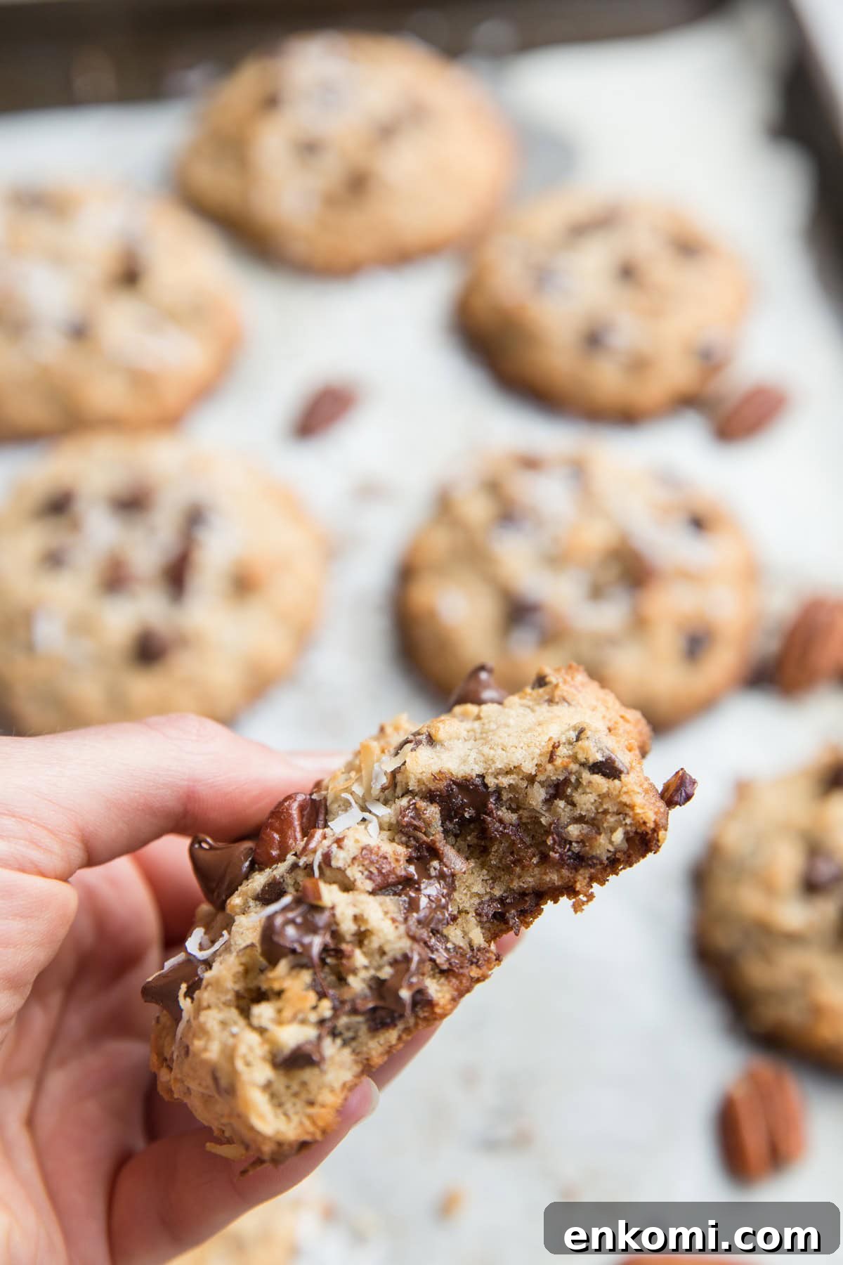 Hand holding a cookie with a bite taken out to see the gooey chocolate inside.