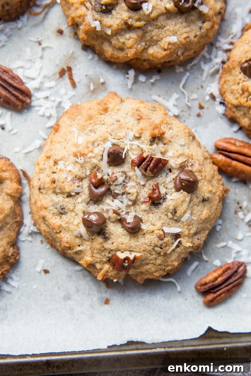 Cookies on a cookie sheet with pecans, chocolate chips, and shredded coconut.