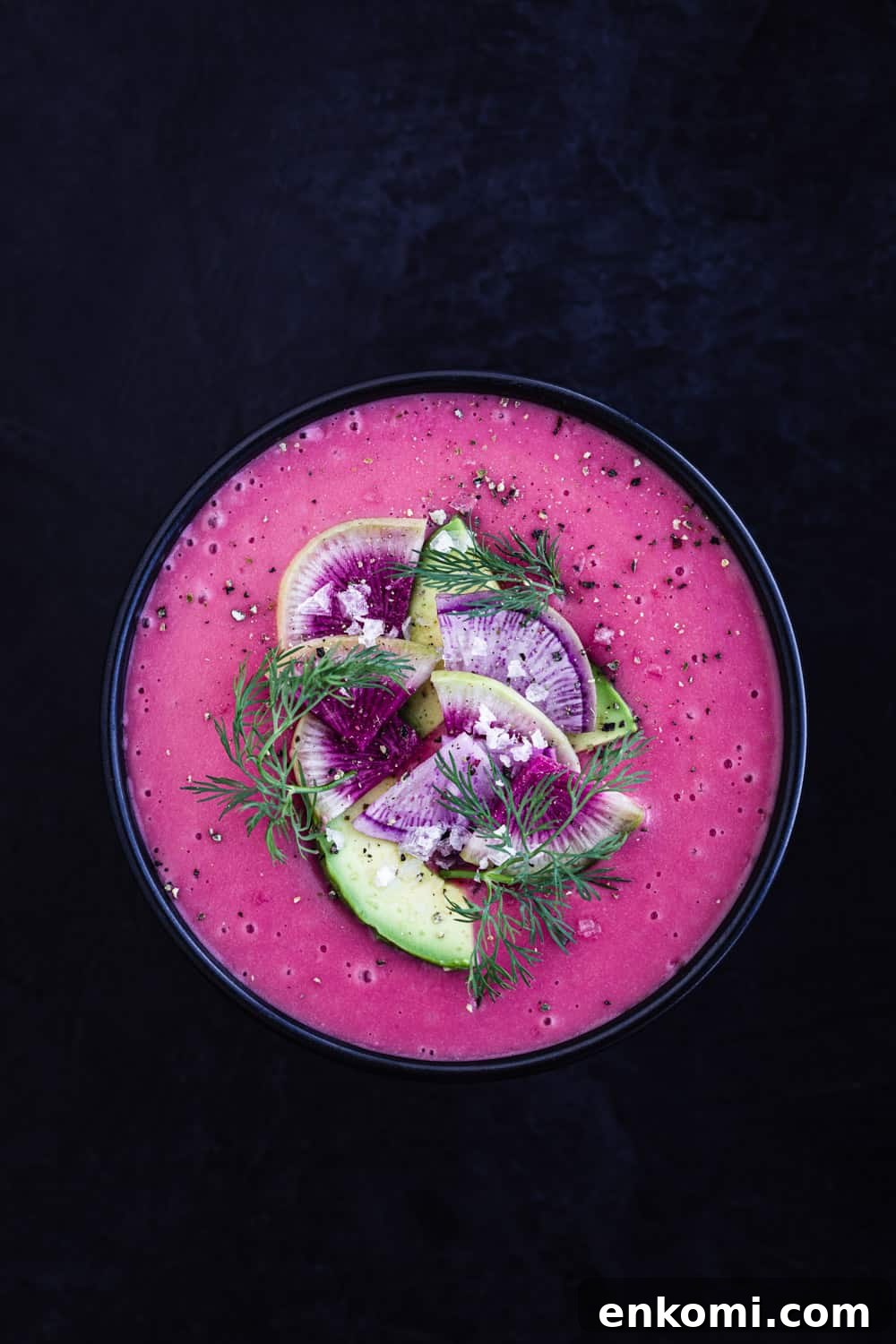 bowl of vegan potato soup garnished with radish, avocado and dill overhead shot.