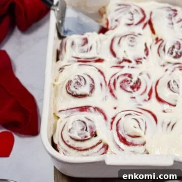 Homemade Red Velvet Cinnamon Rolls with Cream Cheese Glaze 14 The red velvet cinnamon rolls are in a baking dish with a pie cutter in the baking dish.