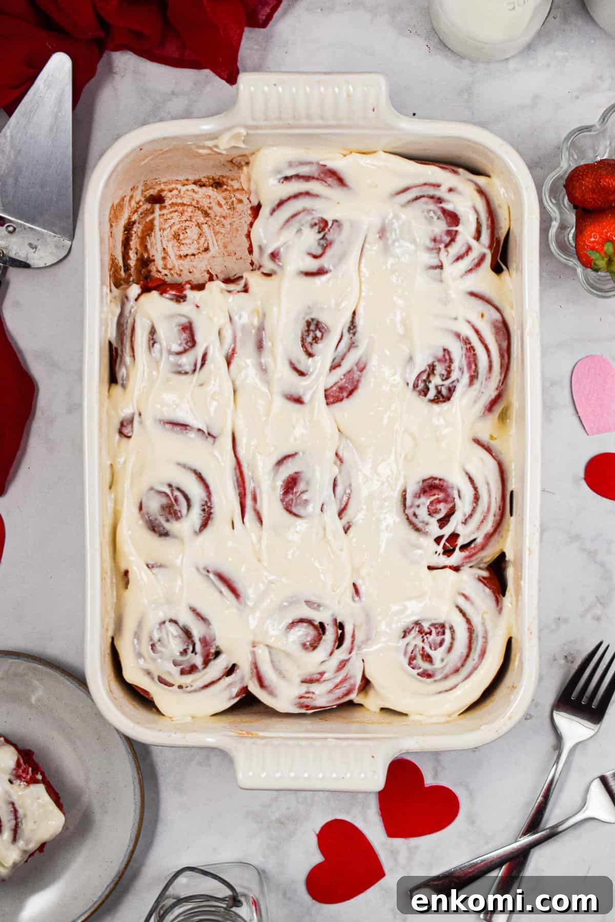 Homemade Red Velvet Cinnamon Rolls with Cream Cheese Glaze 3 One red velvet cinnamon roll is taken out of the corner of the baking dish.