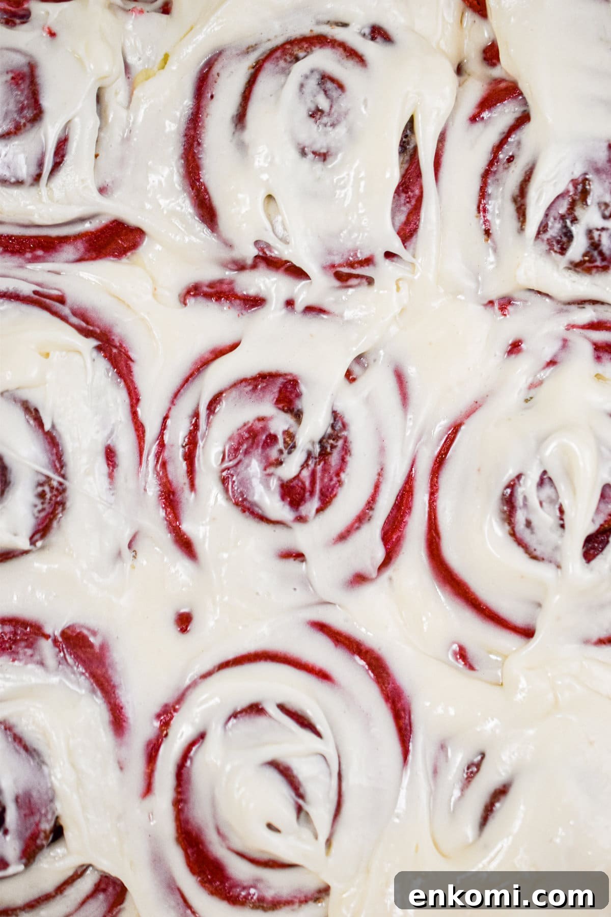 Homemade Red Velvet Cinnamon Rolls with Cream Cheese Glaze 8 Nine red velvet cinnamon rolls are covered with icing.